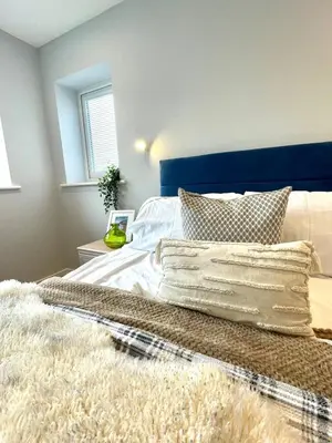 a bedroom with a bed with a blue headboard and pillows at Modern 1 Bed Apartment Sleeps 2 in Llanbadarn-fawr