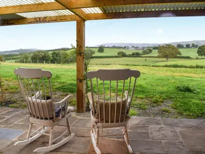 two chairs on a porch with a view of a field at The Cabin in Llangadog