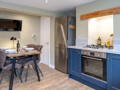 a kitchen with a table and a refrigerator at Pass the Keys Charming 2 Bed Townhouse Short Walk To The River in Shrewsbury