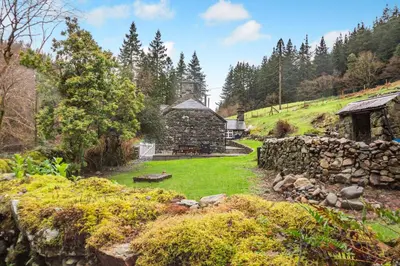 an old stone building in a field with a stone wall at Luxury Cottage near Dolgellau in Llanfachreth