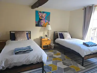 a bedroom with two beds and a painting on the wall at Family room 2 - The Unicorn Hotel in Llanidloes