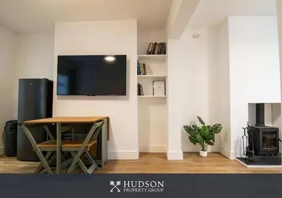a living room with a table and a tv on a wall at Central Oswestry 2 Bedroom House in Oswestry