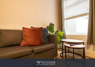 a couch with an orange pillow in a living room at Central Oswestry 2 Bedroom House in Oswestry
