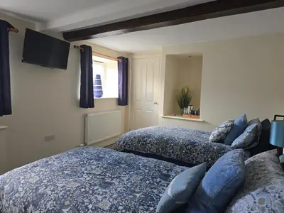 a bedroom with two beds and a tv on the wall at Twin Room - The Unicorn Hotel in Llanidloes