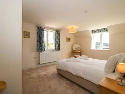 a bedroom with a large bed and two windows at Hoddell Pitch Cottage in Presteigne