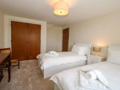 a bedroom with two beds and a desk and a table at Hoddell Pitch Cottage in Presteigne