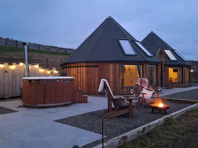 a large wooden cabin with a bench and a hot tub at Yr Awen - Inspiration in Lampeter