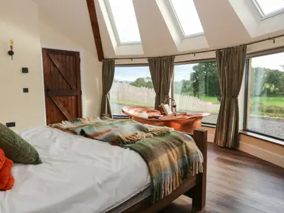 a bedroom with a bed and a table and windows at Ty Crwn - The Roundhouse in Lampeter
