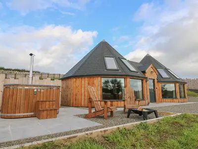 a large wooden cabin with a bench in front of it at Ty Crwn - The Roundhouse in Lampeter
