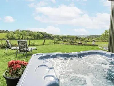 a hot tub in a yard with a chair at Brondel Luxury Shepherd's Hut in Aberystwyth
