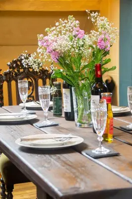 a wooden table with a vase of flowers and wine bottles at Salem The Blue Chapel in Llwyngwril