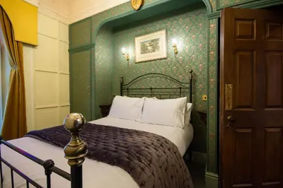 a bedroom with a bed with a green wall at Salem The Blue Chapel in Llwyngwril