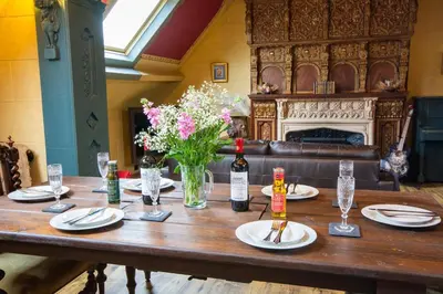 a wooden table with plates and bottles of wine and flowers at Salem The Blue Chapel in Llwyngwril