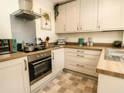 a kitchen with white cabinets and a stove top oven at 6 Upperfield Street in Dolgellau