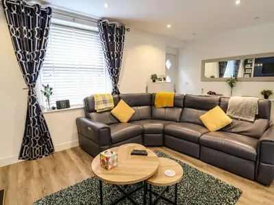 a living room with a leather couch and a table at 6 Upperfield Street in Dolgellau