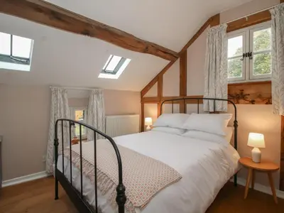 a bedroom with a bed and two windows at Malt House in Bishops Castle