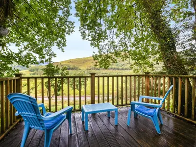 two blue chairs and a table on a deck at The Owl's Nest - Uk50546 in Machynlleth