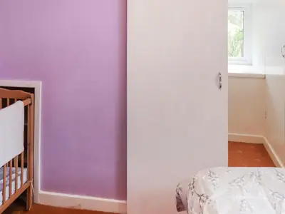 a bedroom with purple walls and a crib at Cynfal Fawr Farmhouse in Ffestiniog