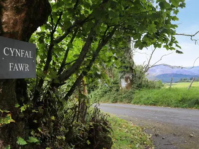 a sign on a tree next to a road at Cynfal Fawr Farmhouse in Ffestiniog