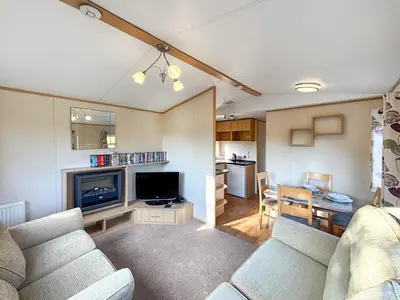 a living room with a couch and a television and a kitchen at Hafren View in Machynlleth