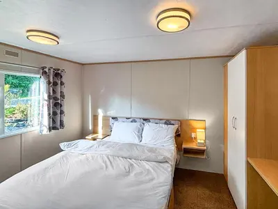 a bedroom with a bed with white sheets and a window at Hafren View in Machynlleth