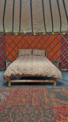a bed in a yurt with a red wall at Hillside Retreats in Machynlleth