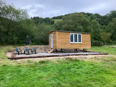 a small cabin with a table and chairs in a field at The Rheidol Shepherds Hut in Aberystwyth