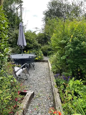 an umbrella sitting on a table in a garden at Patchwork cottage - Grade 2 listed cottage in Snowdonia in Maentwrog
