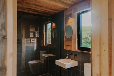 a bathroom with a sink and a mirror at Woolly Wood Cabins - Nant in Abbey-Cwmhir