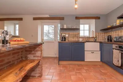 a kitchen with blue cabinets and a brick wall at Cefn-Isaf in Llanbedr