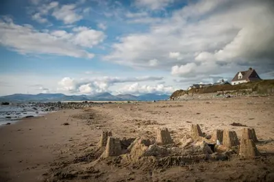 a sand castle on a beach with a house in the background at Cefn-Isaf in Llanbedr