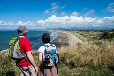 two people standing on a hill looking at the beach at Y-Berllan in Dyffryn