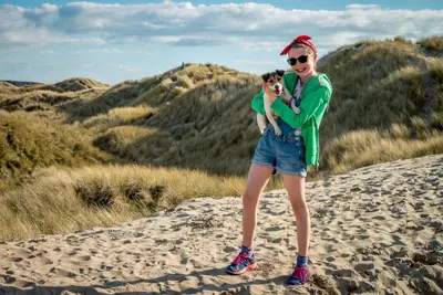 a woman standing on a beach holding a dog at Y-Berllan in Dyffryn