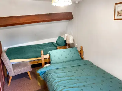 a small room with two beds and a chair at Lower Rheol in Erwood