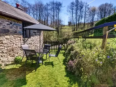 a garden with a table and chairs and an umbrella at Lower Rheol in Erwood