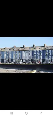 a large blue building next to a body of water at Seaview Apartment in Aberystwyth