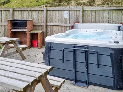 a hot tub in a backyard with a picnic table and a bench at The Dairy -Uk50616 in Corwen
