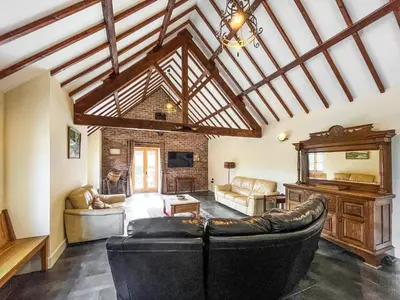 a living room with leather furniture and a large ceiling at The Dairy -Uk50616 in Corwen