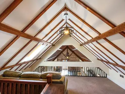 a living room with a vaulted ceiling with wooden beams at The Dairy -Uk50616 in Corwen