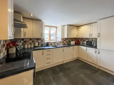 a kitchen with white cabinets and black counter tops at The Dairy -Uk50616 in Corwen