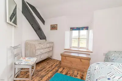 a bedroom with a bed and a dresser and a window at Pwll-Y-March in Llanbedr