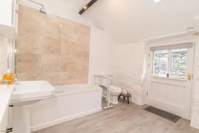 a bathroom with a tub and a sink and a toilet at Pwll-Y-March in Llanbedr