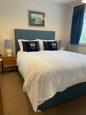 a bedroom with a large bed with a blue headboard at Vicarage Court detached bungalow in Oswestry