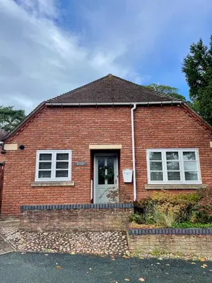 a red brick house with a white door at Vicarage Court detached bungalow in Oswestry