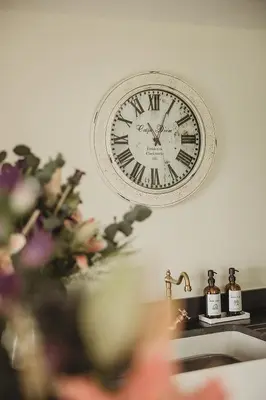 a clock hanging on a wall above a sink at Ty Mawr, The Old School Holiday Homes - Pet Friendly in Llanwrtyd Wells