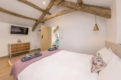 a bedroom with a white bed and a tv at Stabl-Bennar in Dyffryn