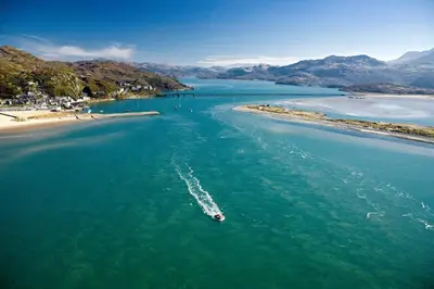 a boat in the water next to a beach at Stabl-Bennar in Dyffryn