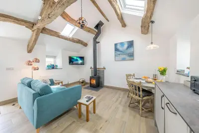 a kitchen and living room with a blue couch and a table at Stabl-Bennar in Dyffryn