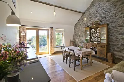 a dining room with a table and a stone wall at Hen-Feudy in Dyffryn