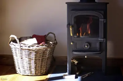 a wood stove with a basket next to it at Hen-Feudy in Dyffryn